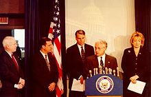 Five men in suits behind a podium.