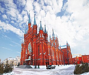 הקתדרלה הקתולית של מוסקבה. הקתדרלה אדומה, ולה צריכים רבים שצבעם כסוף. הקתדרלה במרכז התמונה, השטח לפניה מכוסה שלג, והשמיים מעליה מעוננים חלקית.