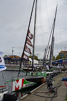 Vu de trois quarts avant, voilier noir et vert amarré au ponton.