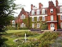 Large, red-brick three-story building; there is a sunken ornamental garden in front.