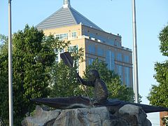 WIS 52 crossing the Wisconsin River, with a kayaking statue in the park and the Dudley Tower in the background