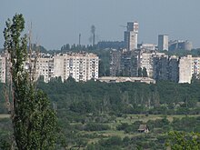 Mine in the distance, behind apartment buildings and green space