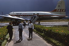 A TACA International Airlines Douglas DC-4 on the ground with people exiting from the rear-left door