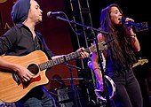 A man and a woman singing together with the man playing guitar