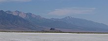 Flat expanse with a mountain range in the distance.