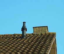 Extrémité d'un faitage scellé sur un toit de doubles pannes en béton avec sortie de ventilation et cheminée maçonnée