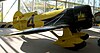 A brilliantly painted black-and-yellow taildragger aircraft, with a massive radial engine and a the racing number "4" on its side.