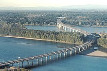 Aerial view of a highway bridge on columns crossing a river and a narrow island.