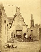 Photographie de la galerie des Cerfs dont la toiture a entièrement disparu, et dont les murs sont en ruine. Au fond, des membres de la Société d'archéologie lorraine fouillent dans les débris pour tenter de retrouver des restes d'oeuvres.