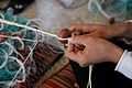 A plastic float being sewn onto a net