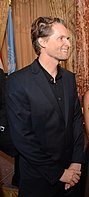 blonde-haired man in a black shirt and suit.