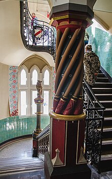 colorful staircase sculpted out of stone with a big column at the forefront. In the background, an owl statue perched on a thin column within the staircase.