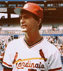 A young, dark-haired man wearing a white baseball uniform with "Cardinals" across the chest in red script and a red baseball cap with an interlocking white "StL"