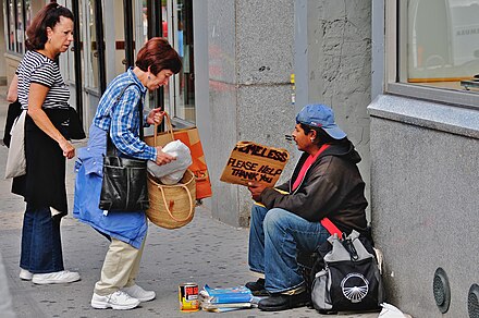 Femme donnant de l'argent à un sans-abri