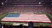 A large flag displayed during the signing of The Star-Spangled Banner prior to the start of an NFL game.