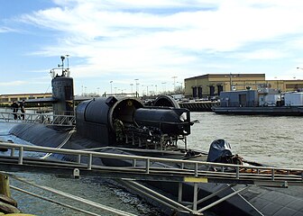 A SEAL Delivery Vehicle (SDV) is loaded aboard the Los Angeles-class fast attack submarine USS Dallas. A Dry Deck Shelter (DDS) is attached to the submarine's forward escape trunk to provide a dry environment for Navy Seals to prepare for special warfare exercises or operations. DDS is the primary supporting craft for the SDV