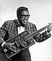 Publicity portrait of American blues musician Bo Diddley, 1957, sitting with his "Twang Machine", a unique square electric guitar built for him by Gretsch.