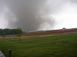 A tornado in the middle of the fields striking a motor plant.
