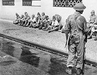 A soldier from the 5th Indian Division stands guard over Japanese prisoners
