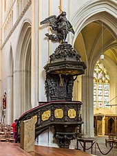 Photographie d'une chaire à prêcher en bois ornée de panneaux sculptés dorés