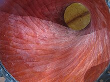 Spiral pattern on the inside of a well-carved djembe made of djalla wood. The spine of the skin is clearly visible through the hole in the waist