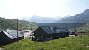 Alte Silvretta-Hütte (das frühere Waschhaus), dahinter die Staumauer des Silvretta-Stausees.