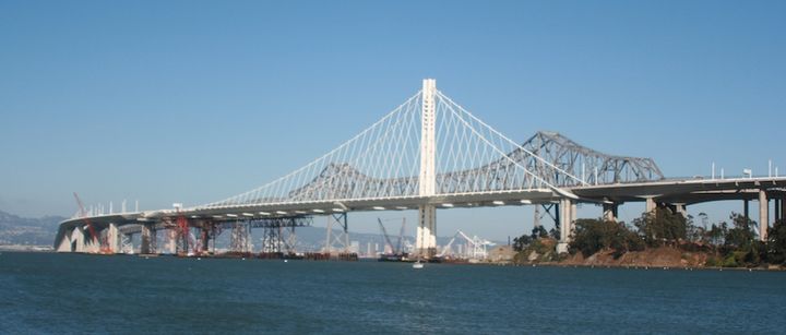 July 7, 2013: The new span is structurally complete and self-supporting. The cable catwalks have been removed and the tower frame disassembled - the remaining temporary falsework is being removed from the eastern end of the main span.