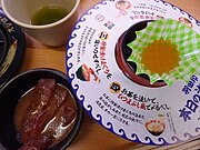 水産会社の羽田市場とのコラボメニュー「羽田印 本日の海鮮丼」と黄身醤油と別皿で付属する漬けマグロ[30]