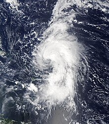 Satellite image of a tropical cyclone in open water. Cloud activity stretches three-fourths the way around the cyclone, and the center is partially exposed.
