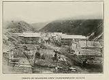 B&W photograph of a street of ramshackle wooden buildings