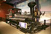 Reuben Wells, an old steam engine on display in a museum, against a painted backdrop