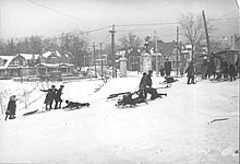 group of people, some on toboggans, on snowy white hillside