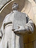 A statue at the Palace of Culture and Science (1955) in Warsaw, holding a book of works by Karl Marx, Friedrich Engels and Vladimir Lenin