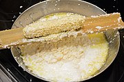 The corn is scraped off the cob into a cooking pan