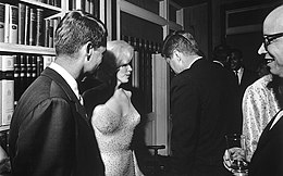 Photograph at a party. From left to right are Robert Kennedy, Marilyn Monroe, John F Kennedy and Arthur M. Schlesinger Jr. John F. Kennedy and Monroe appear to be in conversation.