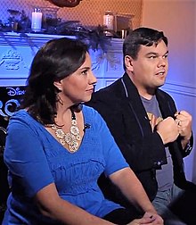 A photograph of Kristen and Bobby Lopez during an interview, seen from the side