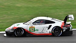 A side view of a predominately while-coloured Porsche 911 RSR being driven in 2018