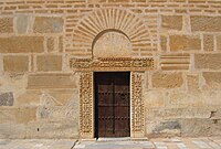 Photographie de la porte du minaret, encadrée d'un linteau et de pieds-droits sculptés d'origine antique. Elle est surmontée d'un arc de décharge en fer à cheval.