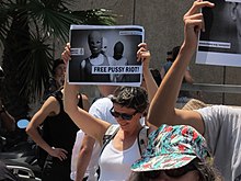 A protester holds a "Free Pussy Riot" sign with a photo of the band members and the insignia of Amnesty International.