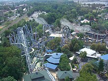 An overhead view of the Great Bear roller coaster among several attractions. The Great Bear roller coaster is left and center of the image, with steel roller coaster SooperDooperLooper located in the middle and left. The Coal Cracker log flume is on the left under the tracks of the Great Bear. The Comet wooden roller coaster is seen in the background, with various paths, buildings, and trees surrounding each attraction.