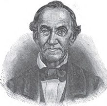 A man with receding black hair, a high-collared white shirt, and a black jacket and bowtie