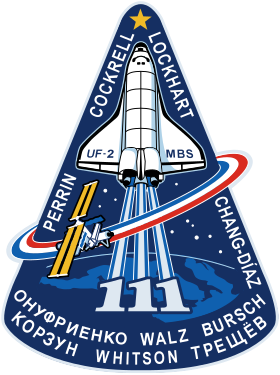 Le logo de la mission STS-111 de la navette spatiale Endeavour vers la Station spatiale internationale en 2002. Les trois « 1 » signifiant le numéro de la mission, de par leur forme verticale, se confondent avec la représentation stylisée des flammes blanches de la navette.