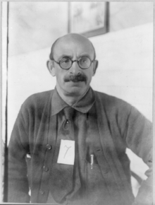 A 49-year-old man with a balding head wearing a pair of glasses