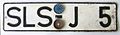 Licence plate with part-plastic (1964); plate and area code are embossed whereas the identifier characters (J 5) are riveted on.