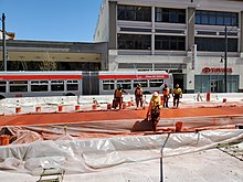 Construction workers smoothing red concrete on an urban street