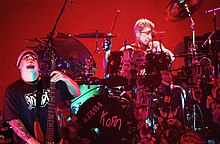 Korn onstage performing under red lights