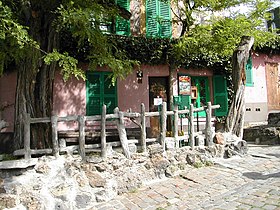 Le banc du Lapin Agile : planté juste devant et partiellement caché par des branches d’arbres en été (2006).