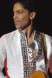 Prince looking towards his right, wearing a white shirt.