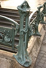 Photo en couleurs d'un potelet de fonte sur une pierre d'angle, légèrement ajouré et sculpté de lignes courbes