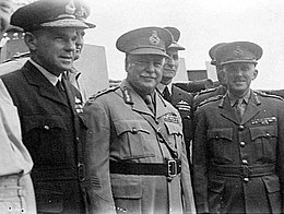 Half portrait of seven men in military uniforms with peaked caps, three featured in foreground